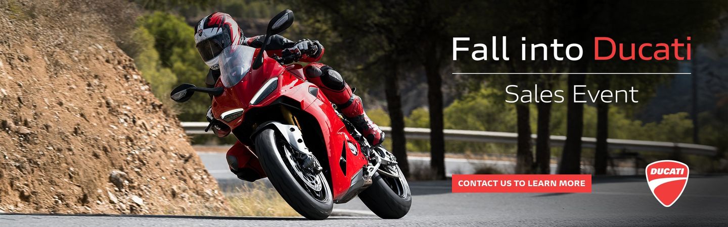 Fall into Ducati sales event. A rider leaning a red Ducati Panigale V4 through a canyon corner.