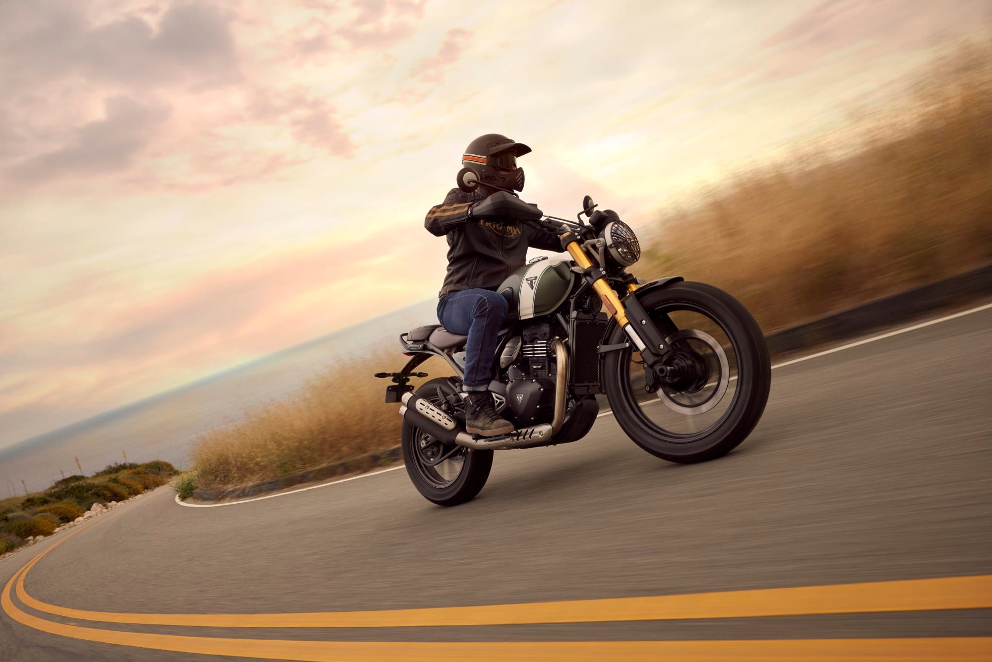 A Scrambler 400 X on a coastal road, photographed by Triumph